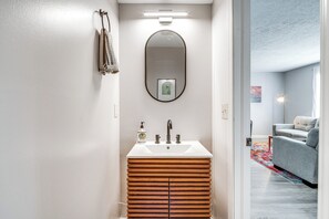 Une salle de bain moderne avec un meuble-lavabo en bois, un grand miroir et un lavabo blanc.