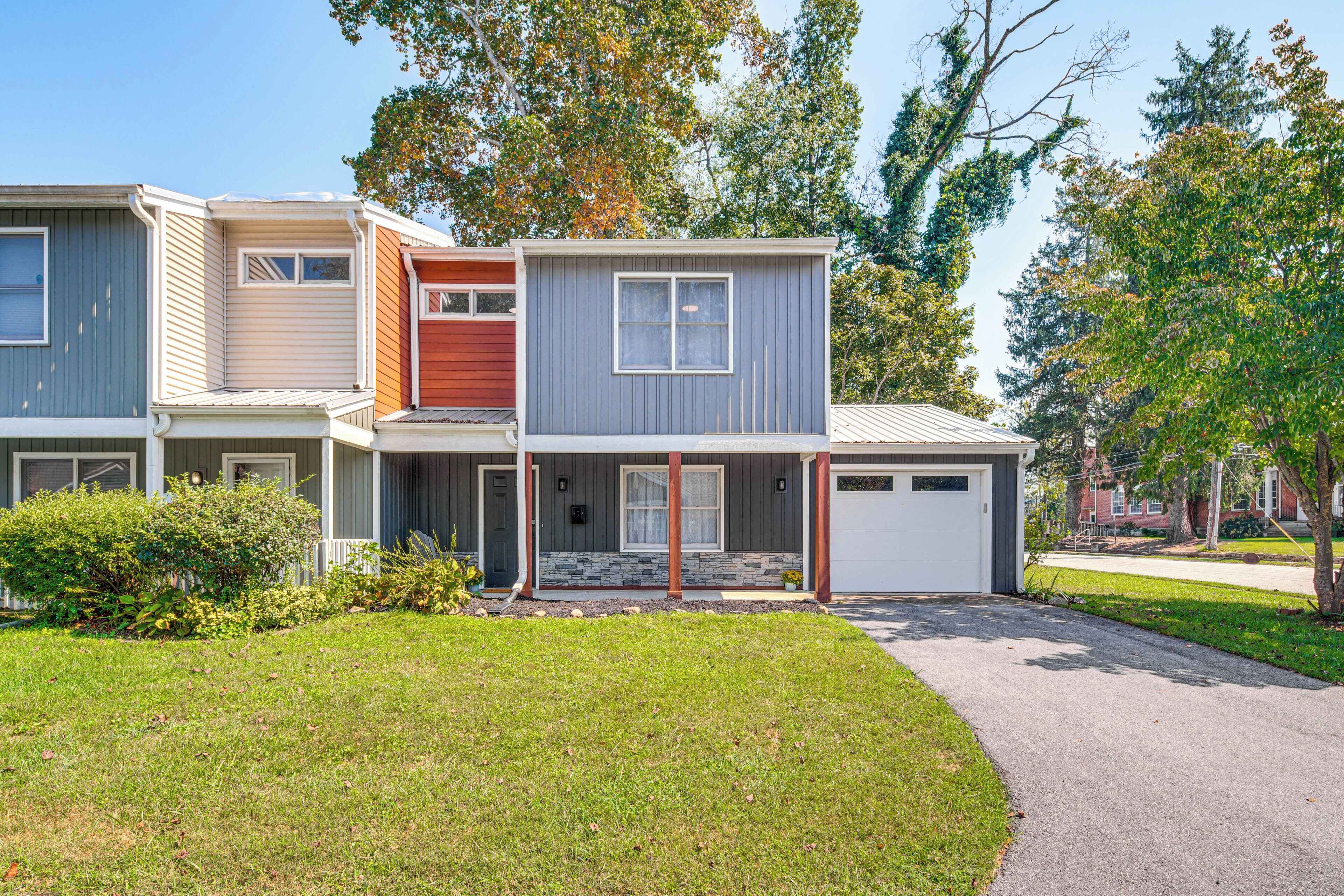 A modern two-story residential building with a garage, a covered porch, and a well-maintained lawn.