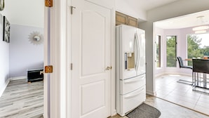 Una cocina moderna con armarios blancos, un refrigerador integrado y un comedor con mesa y sillas.