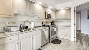 Una cocina moderna con electrodomésticos de acero inoxidable, armarios blancos y salpicadero de azulejos.