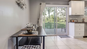 A modern kitchen with a dining area, featuring a large window, white cabinets, and a black dining table. - 1/2 Mi to Creation Museum: Home w/ Large Yard! (Petersburg)