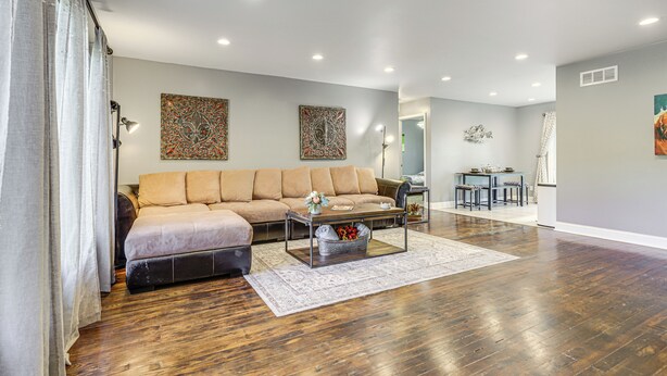 A spacious living room with a sofa, coffee table, and a dining area in the background. - 1/2 Mi to Creation Museum: Home w/ Large Yard! (Petersburg)