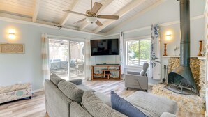 Ein Wohnzimmer mit Sofa, Fernseher, Kamin aus Stein und Deckenventilator.