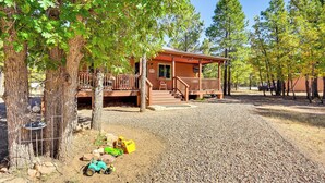 A cabin with a wooden deck, surrounded by trees and gravel. - Hike, Boat & Fish: Serene Cabin in Happy Jack (Happy Jack)
