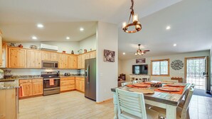 A spacious kitchen with wooden cabinets, stainless steel appliances, and a large island with orange placemats. - Hike, Boat & Fish: Serene Cabin in Happy Jack (Happy Jack)