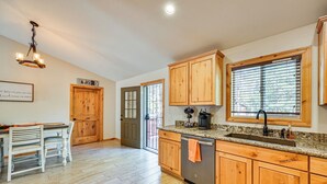 A kitchen with wooden cabinets, a granite countertop, a stainless steel dishwasher, and a window with blinds. - Hike, Boat & Fish: Serene Cabin in Happy Jack (Happy Jack)