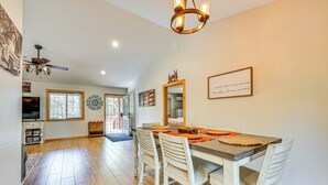 A dining area with a wooden table, white chairs, and a chandelier. - Hike, Boat & Fish: Serene Cabin in Happy Jack (Happy Jack)