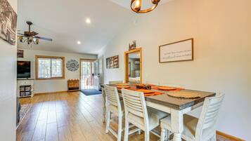 A dining area with a wooden table, white chairs, and a chandelier.