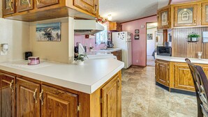 A kitchen with wooden cabinets, a white countertop, and a refrigerator. - Paden City Home Near Ohio River! (Paden City)