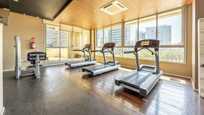 Une salle de sport équipée de tapis de course, d’un vélo d’appartement et d’une machine de musculation.