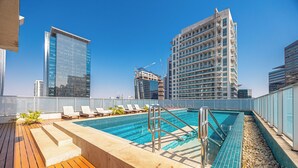Une piscine sur le toit, dotée de chaises longues et offrant une vue sur les immeubles environnants.