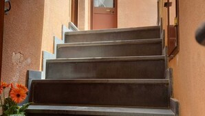 A set of concrete steps leading to a door with a window above it. - "The Tailoring" a thread of history in the heart of the country (Centuripe)