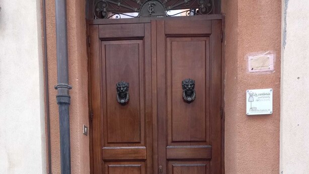 A double wooden door with a metal arch above it, flanked by two steps leading up to the door. - "The Tailoring" a thread of history in the heart of the country (Centuripe)