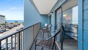 A balcony with wicker chairs, a view of the parking lot, and a building with blue siding. - B325 at the Myrtle Beach Resort (Myrtle Beach)