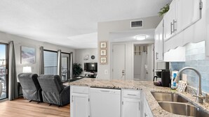 A modern kitchen with white cabinets, a granite countertop, and stainless steel appliances.