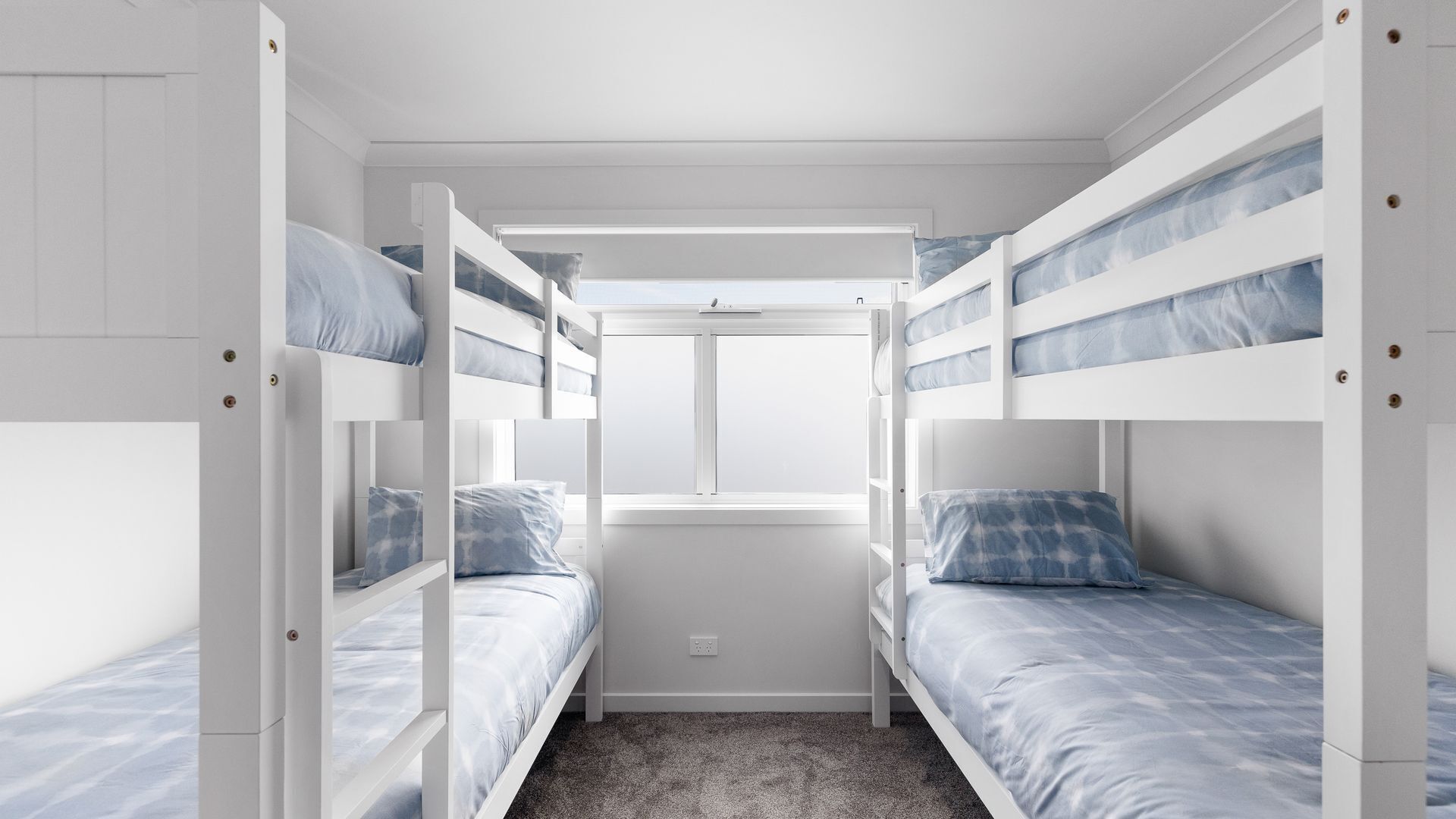 Quarto com beliche, piso coberto por carpete e paredes brancas.