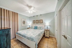 Ein Schlafzimmer mit Bett, Nachttischen, Deckenventilator und einer Tür.