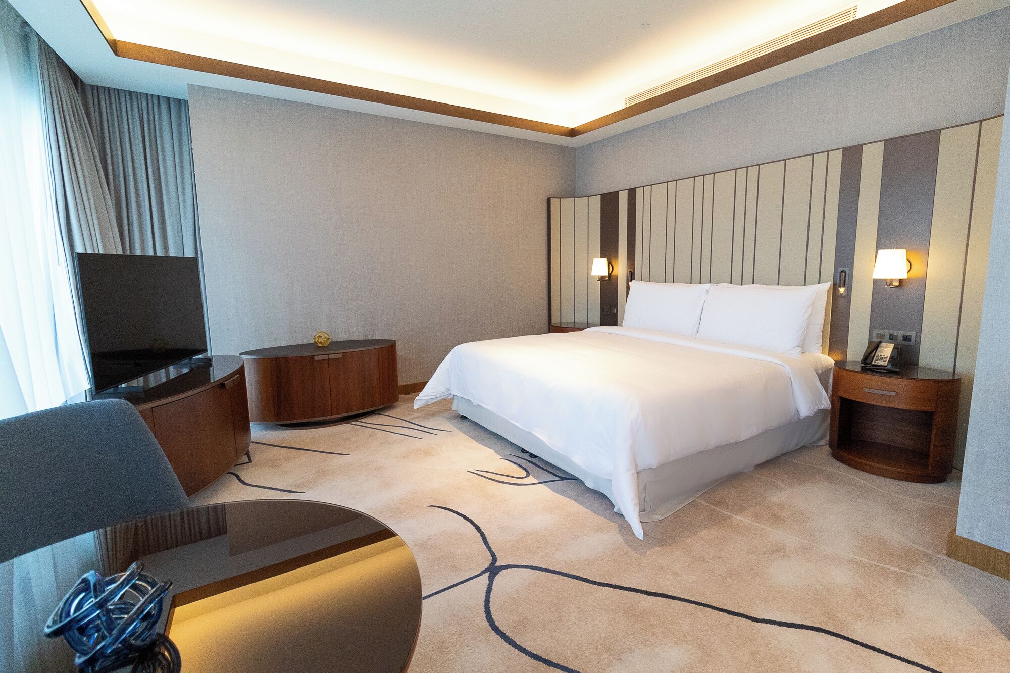 A hotel room with a bed, a TV, a desk, and a chair.