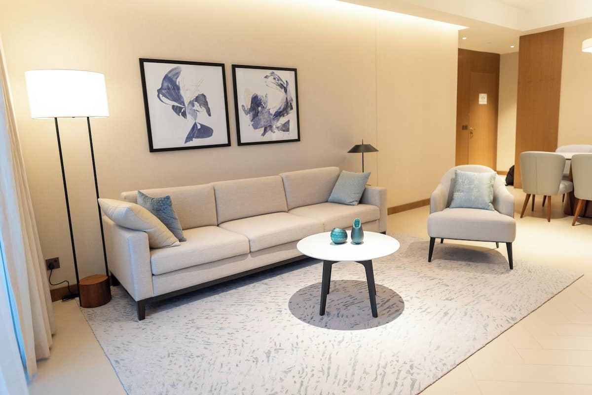A modern living room with a beige sofa, a round coffee table, and two framed abstract paintings on the wall.