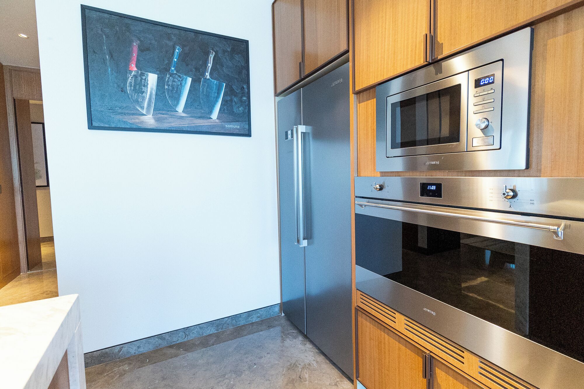 A kitchen with stainless steel appliances, including a refrigerator, microwave, and oven.