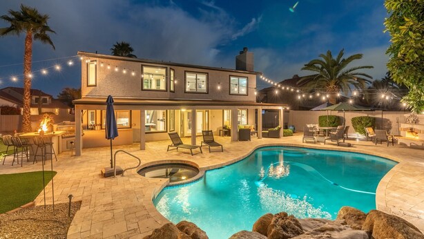 A modern house with a swimming pool, outdoor seating, and string lights.