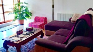 Un soggiorno con un divano, un tavolino da caffè, un pouf a righe, una pianta in vaso e una lampada da terra.