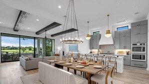 A modern kitchen with grey cabinets, a wooden dining table, and a large island. - Ellen Lake Luxe | Concierge Services (Kingsland)