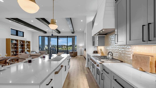 A modern kitchen with a large island, white cabinetry, and a view to the outdoors. - Ellen Lake Luxe | Concierge Services (Kingsland)