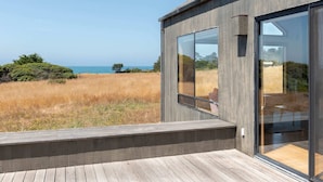 A modern building with large glass windows overlooking a coastal landscape. - Spacious 3 BD for 6 + Ocean View (Sea Ranch)