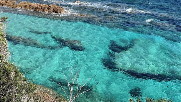 A coastal landscape with clear turquoise waters, rocky outcrops, and a distant lighthouse. - Luxury villa in private estate with sea view and beach access 150 metres away (Zonza Sainte Lucie de Porto Vecchio)