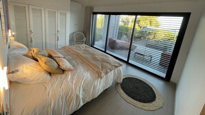 A bedroom with a bed, a chair, a window with blinds, and a ceiling fan. - Luxury villa in private estate with sea view and beach access 150 metres away (Zonza Sainte Lucie de Porto Vecchio)