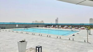 Ein Pool auf dem Dach mit Liegestühlen und Blick auf die Stadt.