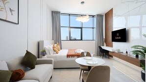 Ein modernes Wohnzimmer mit einer Couch, einem Esstisch und einem an der Wand befestigten Fernseher.