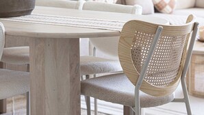 A cozy living room with a wooden dining table, a woven chair, and a potted plant. - Cozy Boho Retreat One Bedroom Sanctuary (Jumeirah Village Circle)