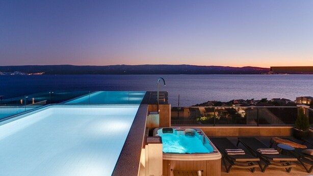 A rooftop infinity pool with a hot tub and lounge chairs overlooking a body of water at sunset. - NEW Seaview Villa Gabriel with private heated pool and a Hot-tub (Stanici)
