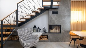 A modern interior with a staircase, a fireplace, a dining area, and a patterned armchair. - NEW Seaview Villa Gabriel with private heated pool and a Hot-tub (Stanici)