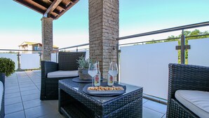 An outdoor patio with wicker furniture, a stone pillar, and a table with snacks and drinks. - Beautiful Casa Nerlović with swimming pool (Vrvari)