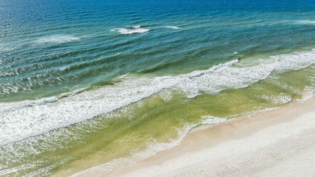 A beach with clear blue water and a sandy shore.