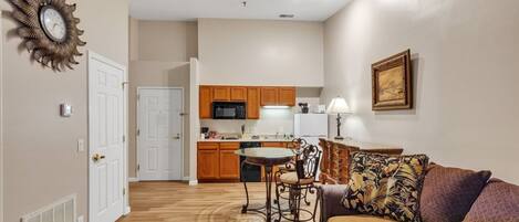 A compact living space with a kitchenette, a dining area, and a seating area with a sofa and a chair.