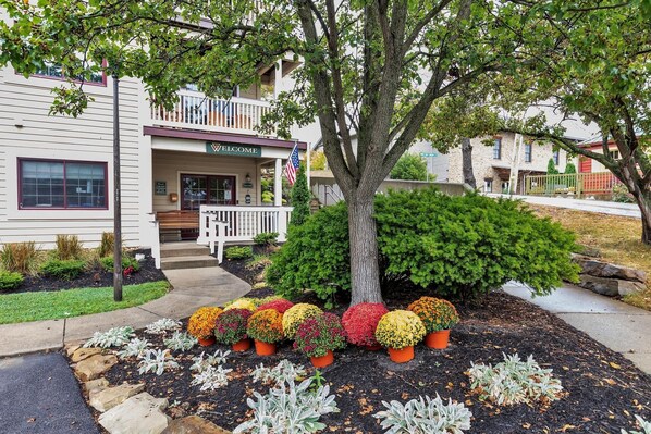 A two-story building with a welcoming entrance, a balcony, and a row of potted plants in front. - 3rd Floor Back Side Corner Penthouse Suite- 305 by Grand Wood Suites (Nashville)