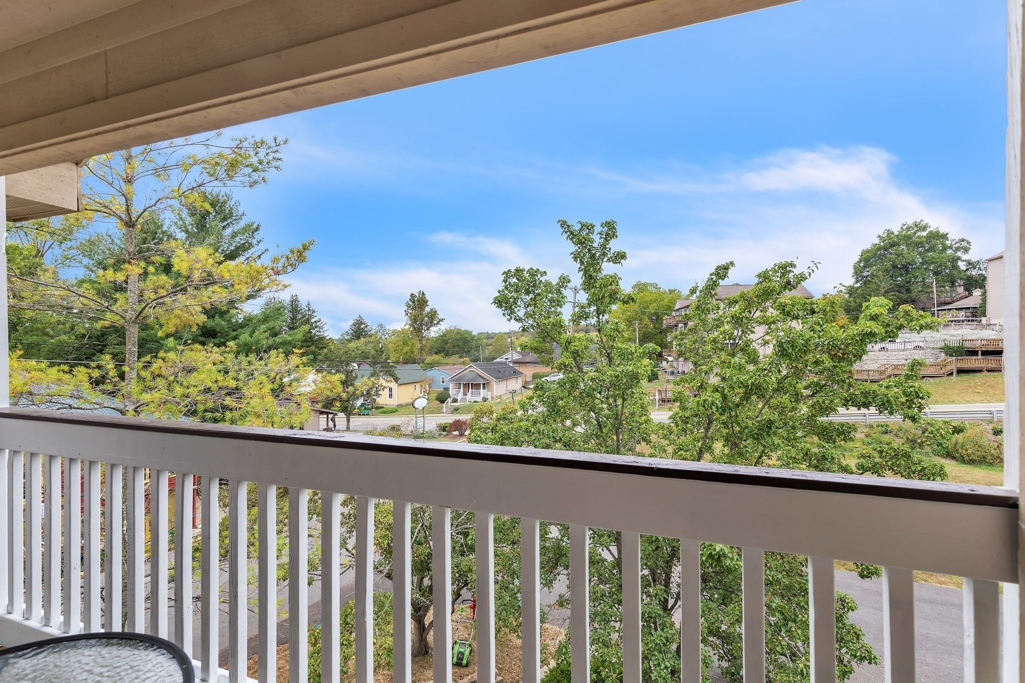 A balcony with a view of a residential neighborhood, including houses and trees.