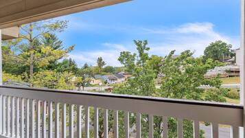 A balcony with a view of a residential neighborhood, including houses and trees.