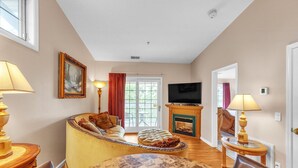 A living room with a sofa, a dining table, a fireplace, and a television. - 3rd Floor Front Side Corner Penthouse Suite - 301 by Grand Wood Suites (Nashville)
