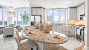 A modern kitchen with granite countertops, white cabinetry, and a large island with seating. - Lagoon Tower 1301 3 Bedroom Condo (Gulf Shores)