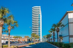 Un grand hôtel moderne à la façade incurvée, entouré de palmiers et doté d’un parking.