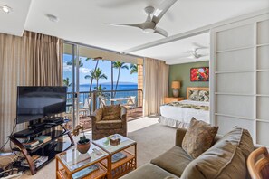 Ein Hotelzimmer mit Balkon, einem Bett, einem Fernseher, einem Couchtisch und einer Couch.