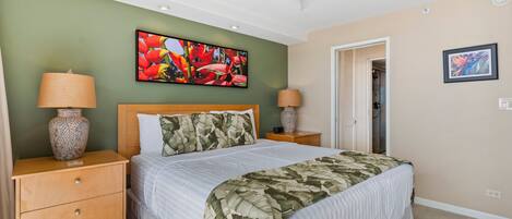 Un dormitorio con una cama, dos mesitas de noche, un ventilador de techo, un televisor y obras de arte en las paredes.