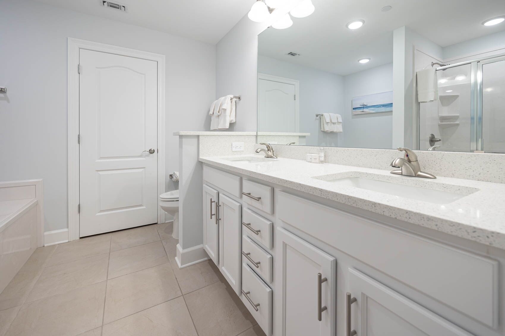 A modern bathroom with a double sink, white cabinetry, and a large mirror.