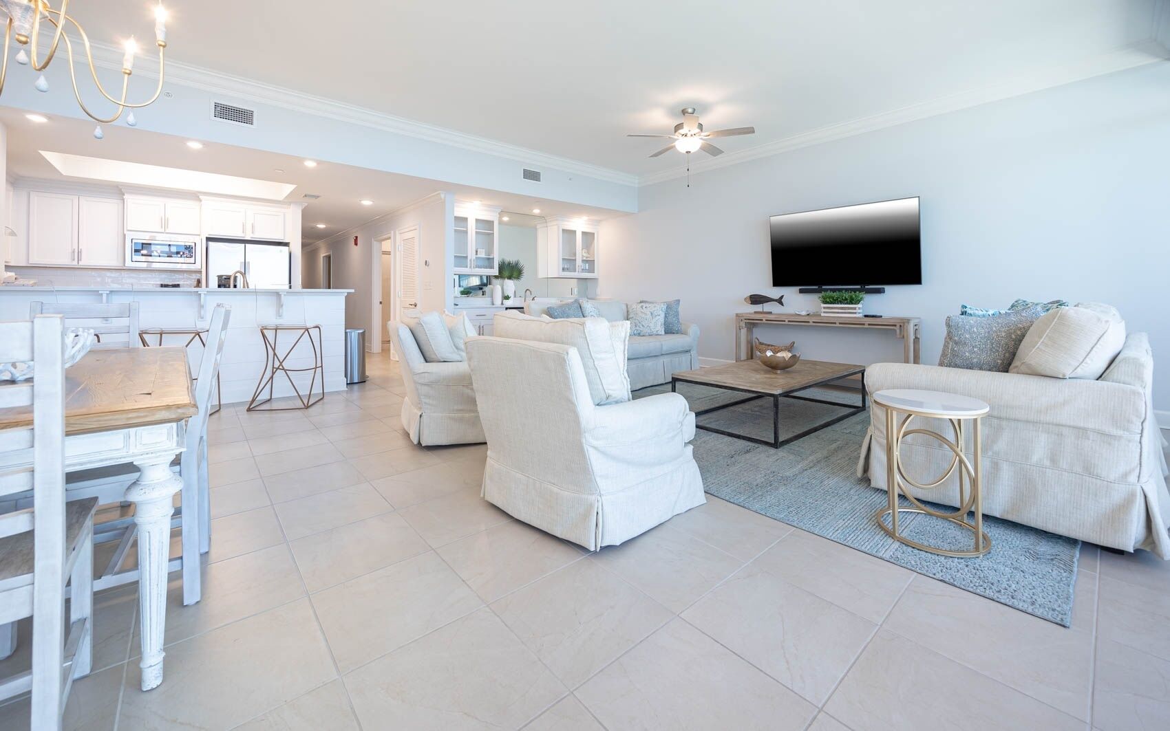 A spacious living area with a dining table and chairs, a sofa, a coffee table, and a TV mounted on the wall.