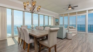 Una habitación amplia con una gran mesa de comedor, asientos cómodos, un candelabro y vistas al océano.